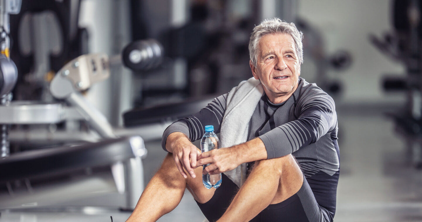 Zufriedener Mann ruht sich nach dem Bewegungstraining im Fitnessraum aus.